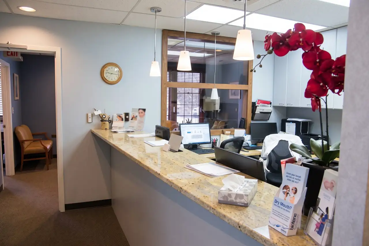 The reception desk at Comprehensive Dental Group, a long granite counter under white pendant lights, on Palmer Avenue in Larchmont.