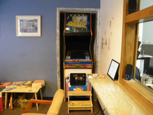 The kids&rsquo; area in the waiting room: an arcade cabinet, a small table and toys.
