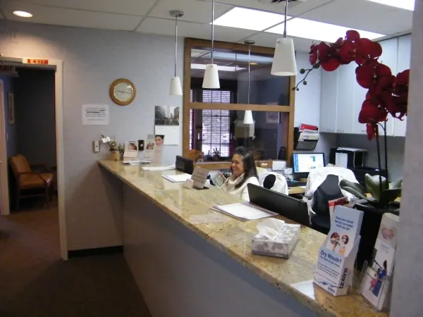 The reception counter at Comprehensive Dental Group, with a red orchid and pendant lights.